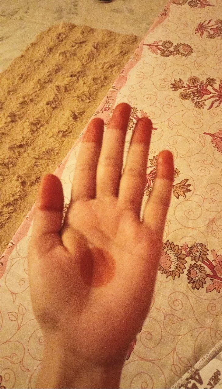 Hand with faded mehndi on patterned fabric