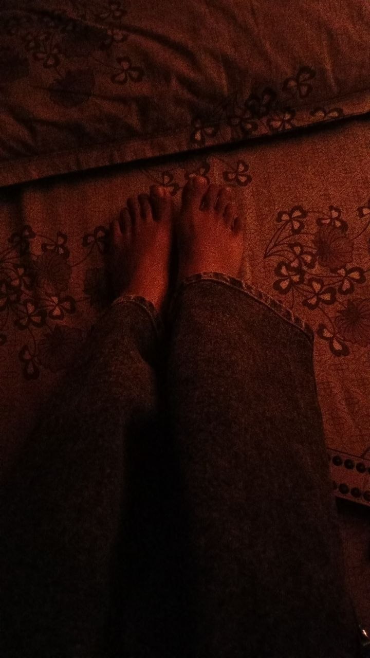 Bare feet on a floral patterned bedspread in warm light